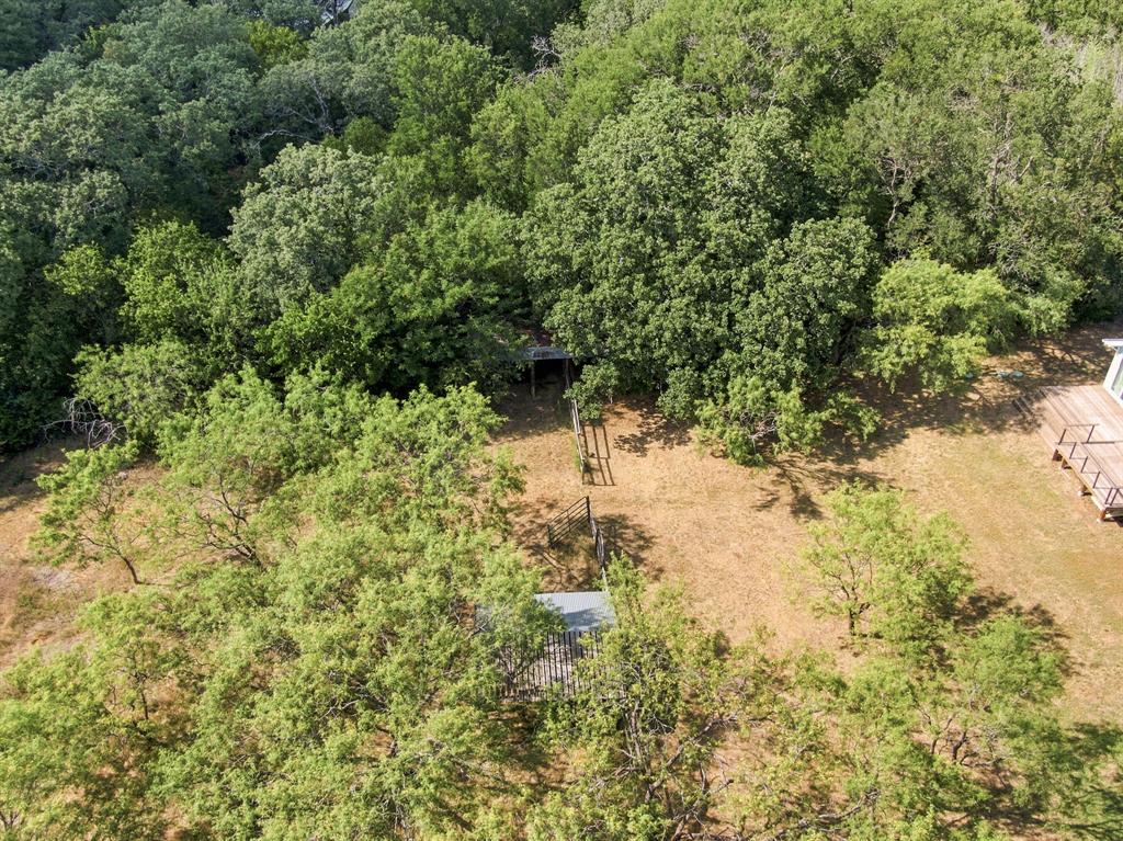 3325 Dove Creek Road Cleburne, TX 76031 - Photo 32 of 40 Expansive outdoor space featuring a large wooden deck, mature trees, and natural landscaping