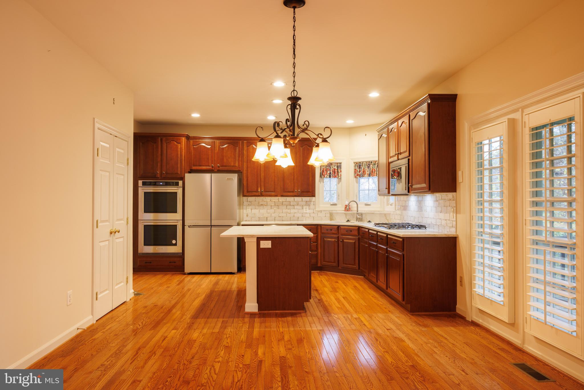 8623 James Creek Drive Springfield, VA 22152 - Photo 18 of 69 a kitchen with stainless steel appliances granite countertop a refrigerator a sink dishwasher a kitchen island with wooden floor and cabinets