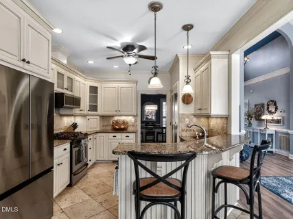 a kitchen with stainless steel appliances kitchen island granite countertop a table chairs and a refrigerator