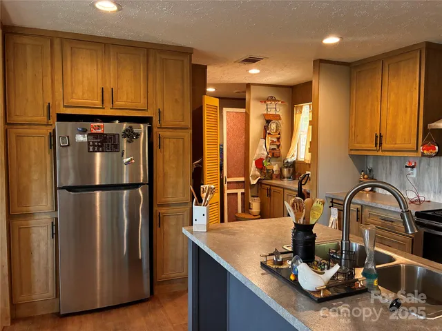 a kitchen with kitchen island granite countertop a refrigerator a stove a sink and a dining table with wooden cabinet