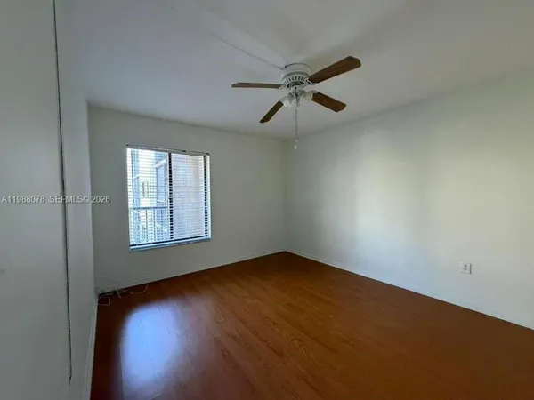 an empty room with a window and a ceiling fan