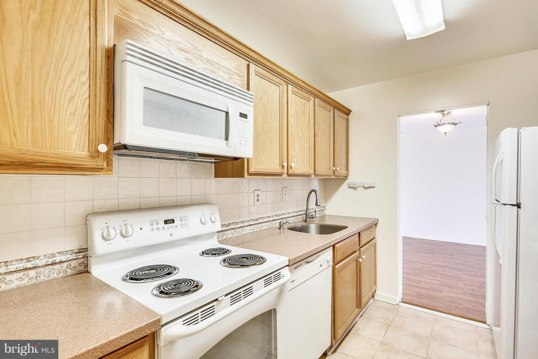 9701 Fields Road, Unit 1604 Gaithersburg, MD 20878 - Photo 5 of 30 a kitchen with a sink a stove and a refrigerator