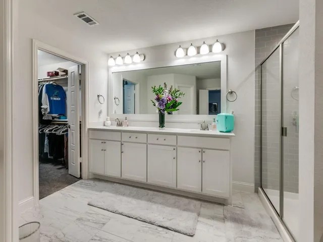 a spacious bedroom with a large bed a chandelier and dresser