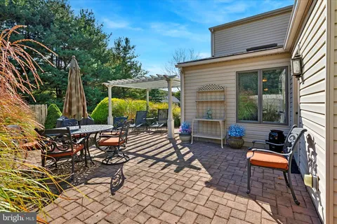 a view of a brick house with a yard plants and large tree