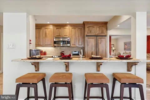 a kitchen with stainless steel appliances a dining table chairs refrigerator and sink