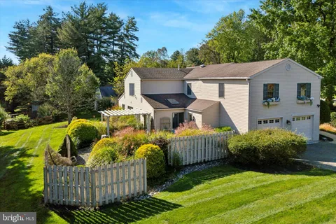 a view of a white house next to a yard with plants and trees