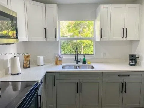 a kitchen with stainless steel appliances granite countertop white cabinets a sink and a window