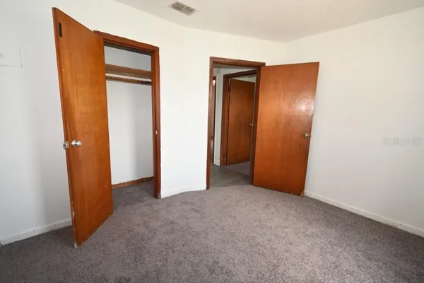an empty room with closet and mirror