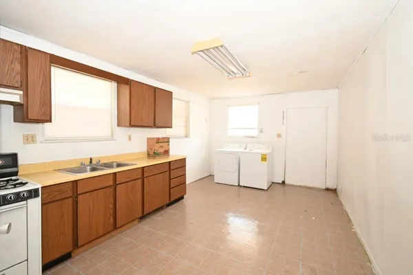 a large white kitchen with a sink window and cabinets