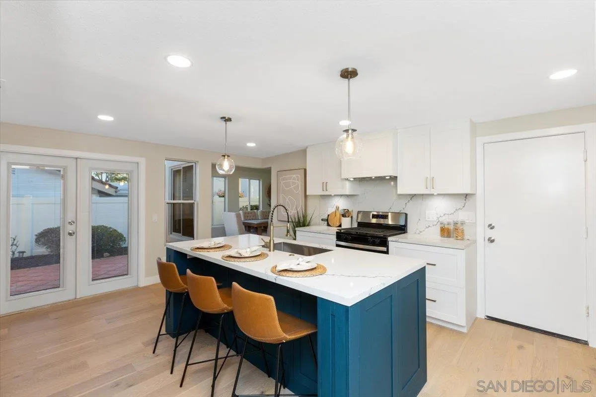 4692 Adra Way Oceanside, CA 92056 - Photo 5 of 51 a kitchen with a sink a stove a refrigerator and white cabinets with wooden floor