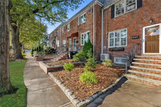 a front view of a house with garden and trees