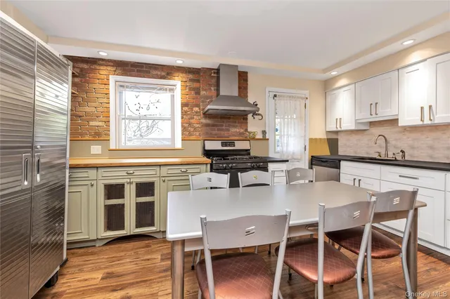 a kitchen with granite countertop a stove top oven cabinets dining table and chairs