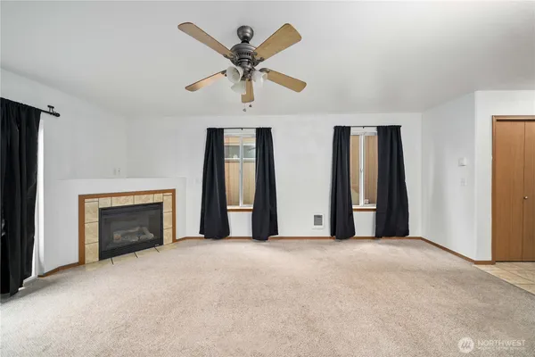 an empty room with windows and fireplace