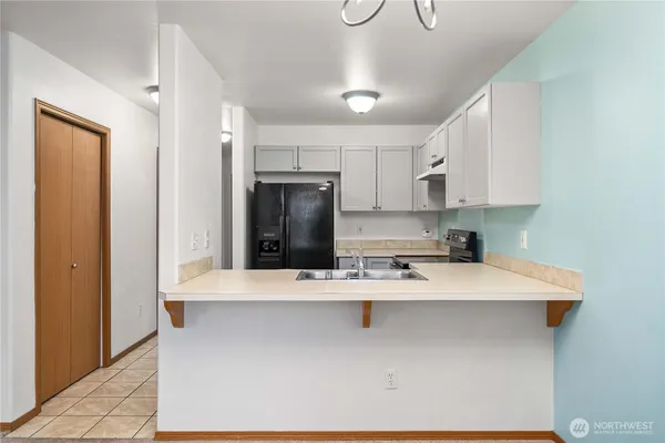 a kitchen with kitchen island a sink a stove a refrigerator and cabinets
