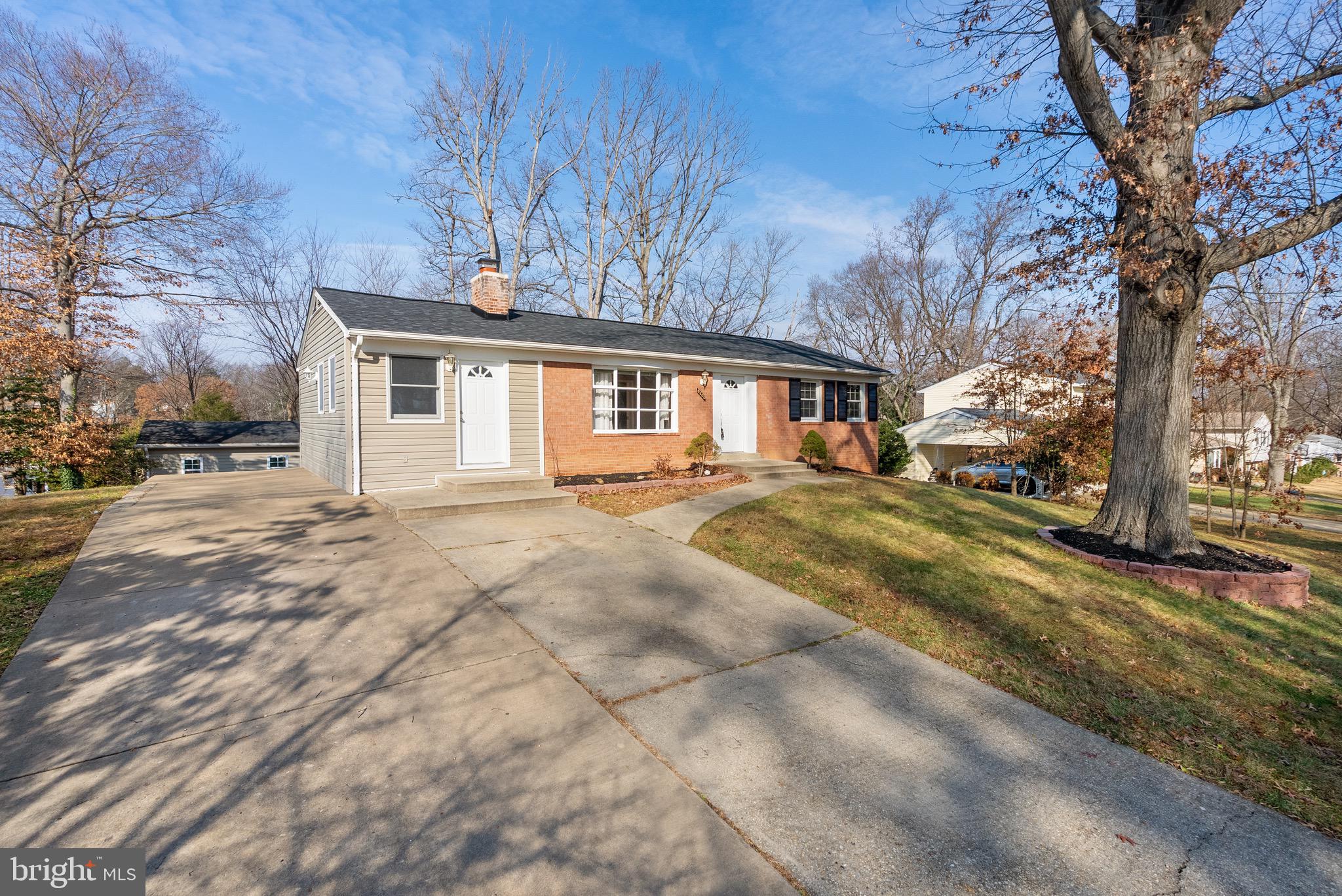 a front view of a house with a yard covered with snow and trees