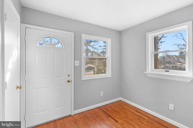 a view of an empty room with window and wooden floor
