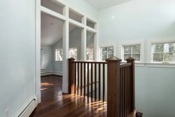 a view of a hallway with wooden floor and windows