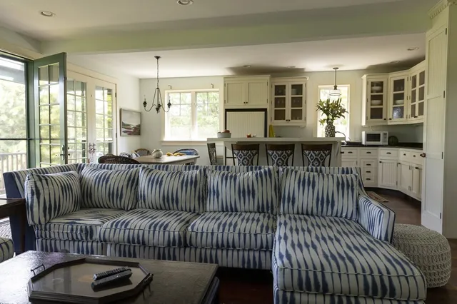 a living room with furniture a fireplace and large windows