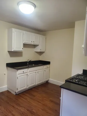 a kitchen with granite countertop a sink cabinets and wooden floor