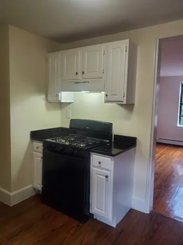 a kitchen with granite countertop a stove and a wooden floors