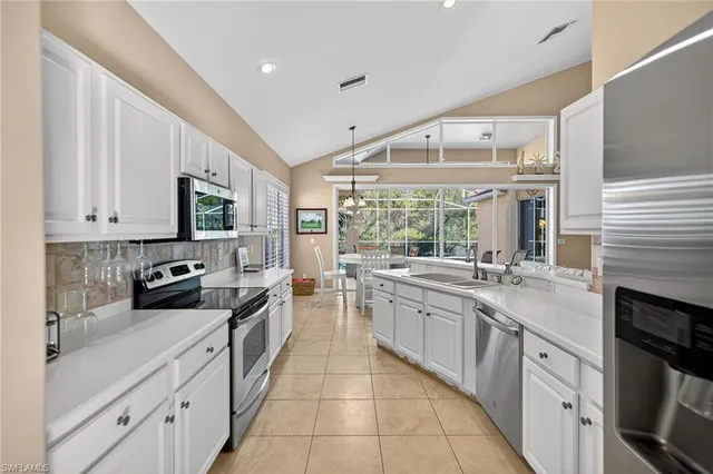 a large white kitchen with a large window a sink and stainless steel appliances