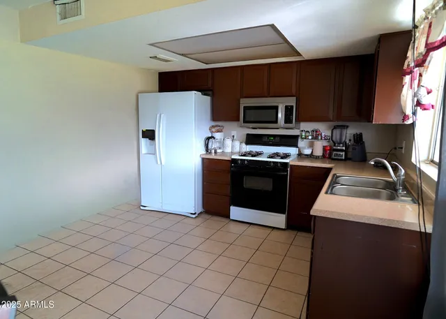 a kitchen with stainless steel appliances granite countertop a stove a sink dishwasher and a refrigerator with wooden cabinets