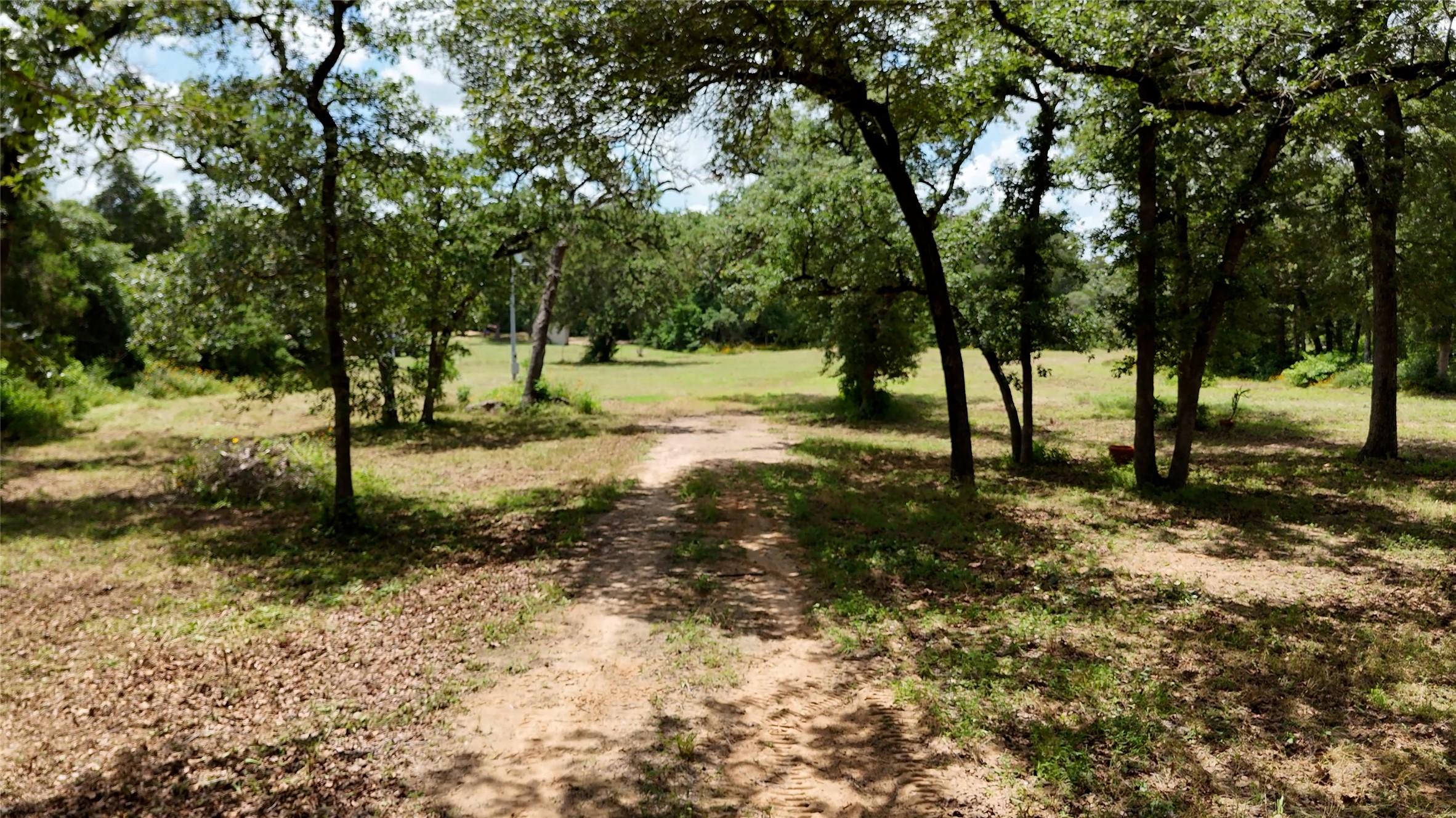 277 Meuth Cemetery Road Red Rock, TX 78662 - Photo 2 of 10 A secluded path winds through a peaceful, verdant landscape, inviting tranquil moments.