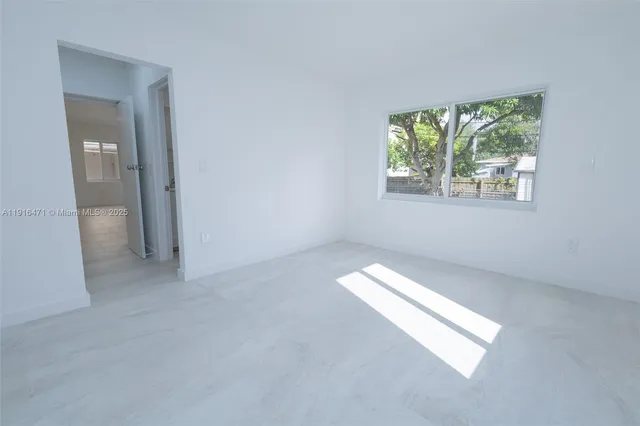 a view of an empty room with closet and a window