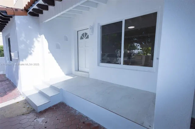 an empty room with windows and kitchen view