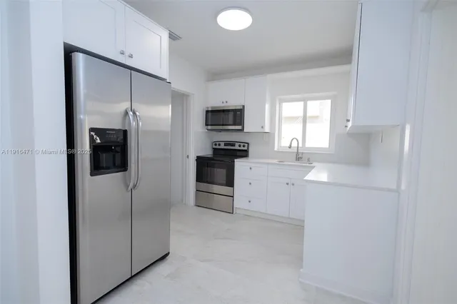 a kitchen with stainless steel appliances a stove a microwave and white cabinets