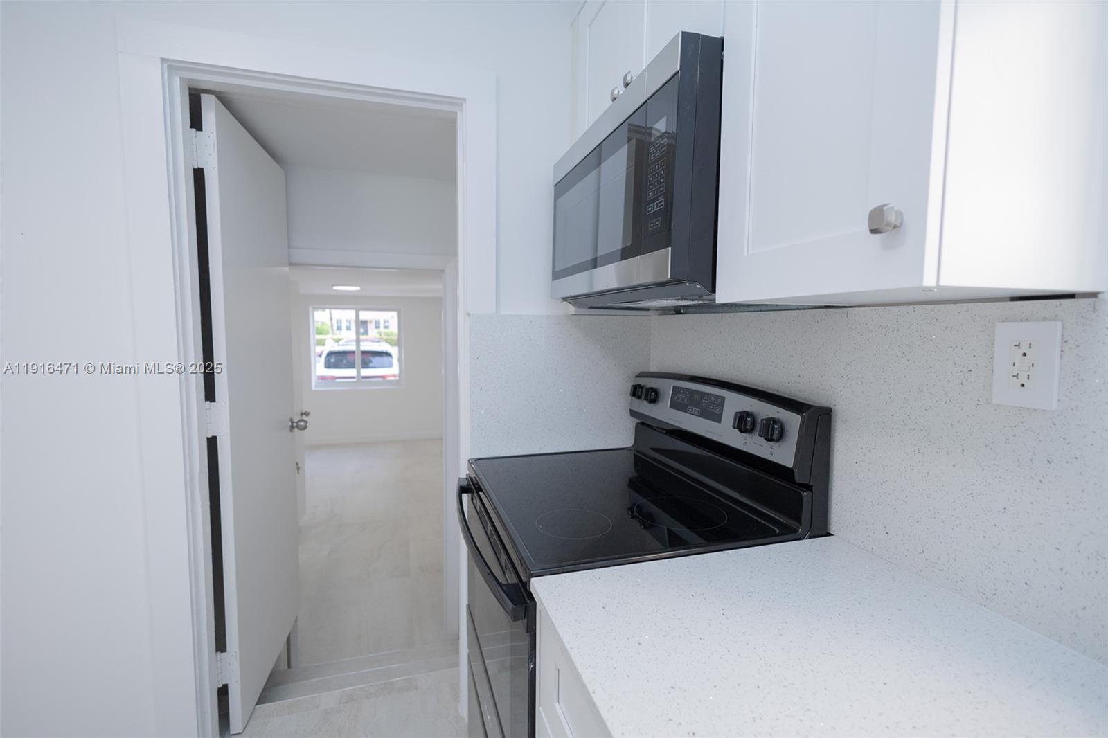 2675 Southwest 24th Terrace Miami, FL 33145 - Photo 9 of 36 a kitchen with stainless steel appliances a stove a microwave and white cabinets