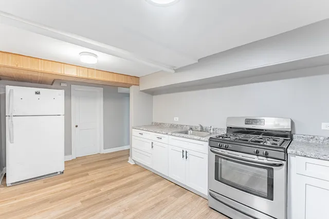 a kitchen with granite countertop a sink cabinets stainless steel appliances and wooden floor