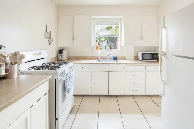 a kitchen with granite countertop a sink a stove and a refrigerator