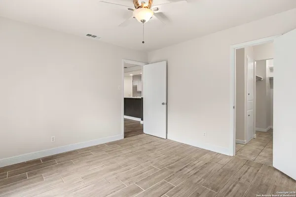 a view of empty room with wooden floor and fan