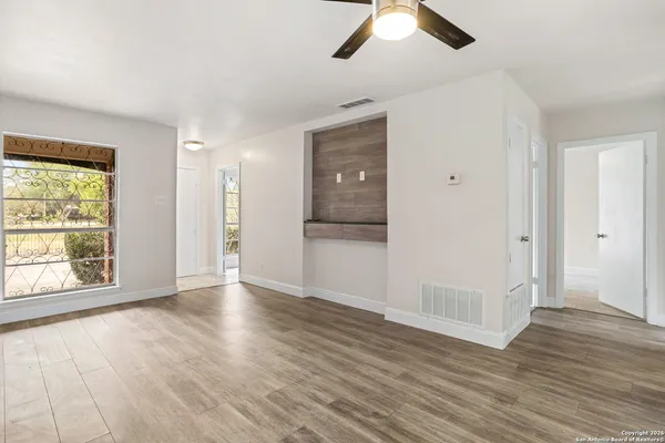 a view of an empty room with wooden floor and window