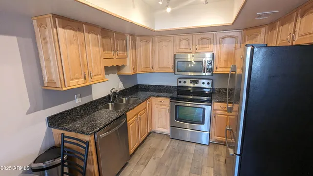 a kitchen with stainless steel appliances granite countertop a stove a refrigerator and a sink