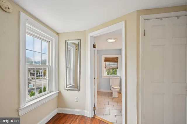 a view of an empty room with window and wooden floor
