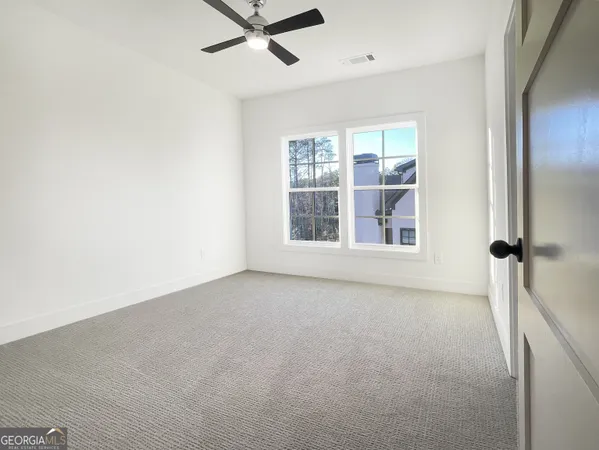 an empty room with ceiling fan and windows