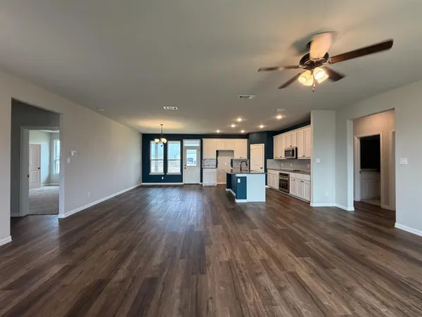 a kitchen with stainless steel appliances granite countertop a stove top oven a sink dishwasher and a refrigerator with wooden floor