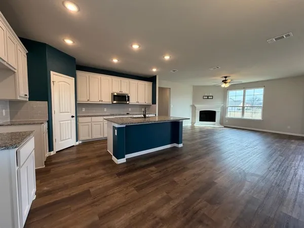 an empty room with wooden floor chandelier fan and windows