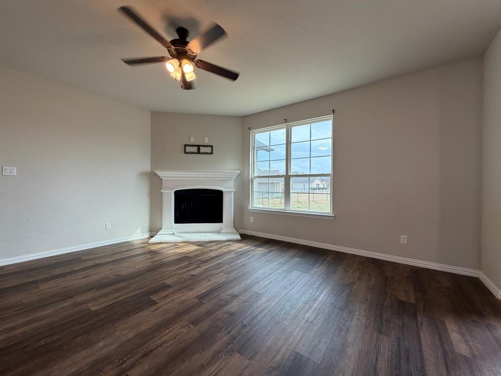 1035 Northern Oaks Court Springtown, TX 76082 - Photo 5 of 15 an empty room with wooden floor chandelier fan and windows