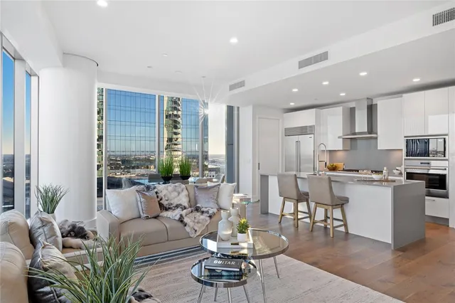 a living room with stainless steel appliances kitchen island granite countertop a table chairs and a refrigerator