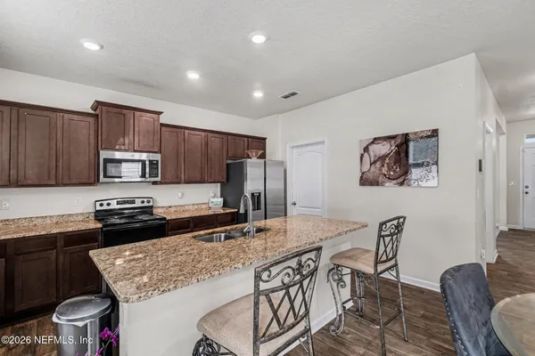 a kitchen with stainless steel appliances granite countertop a stove top oven a sink a dining table and chairs
