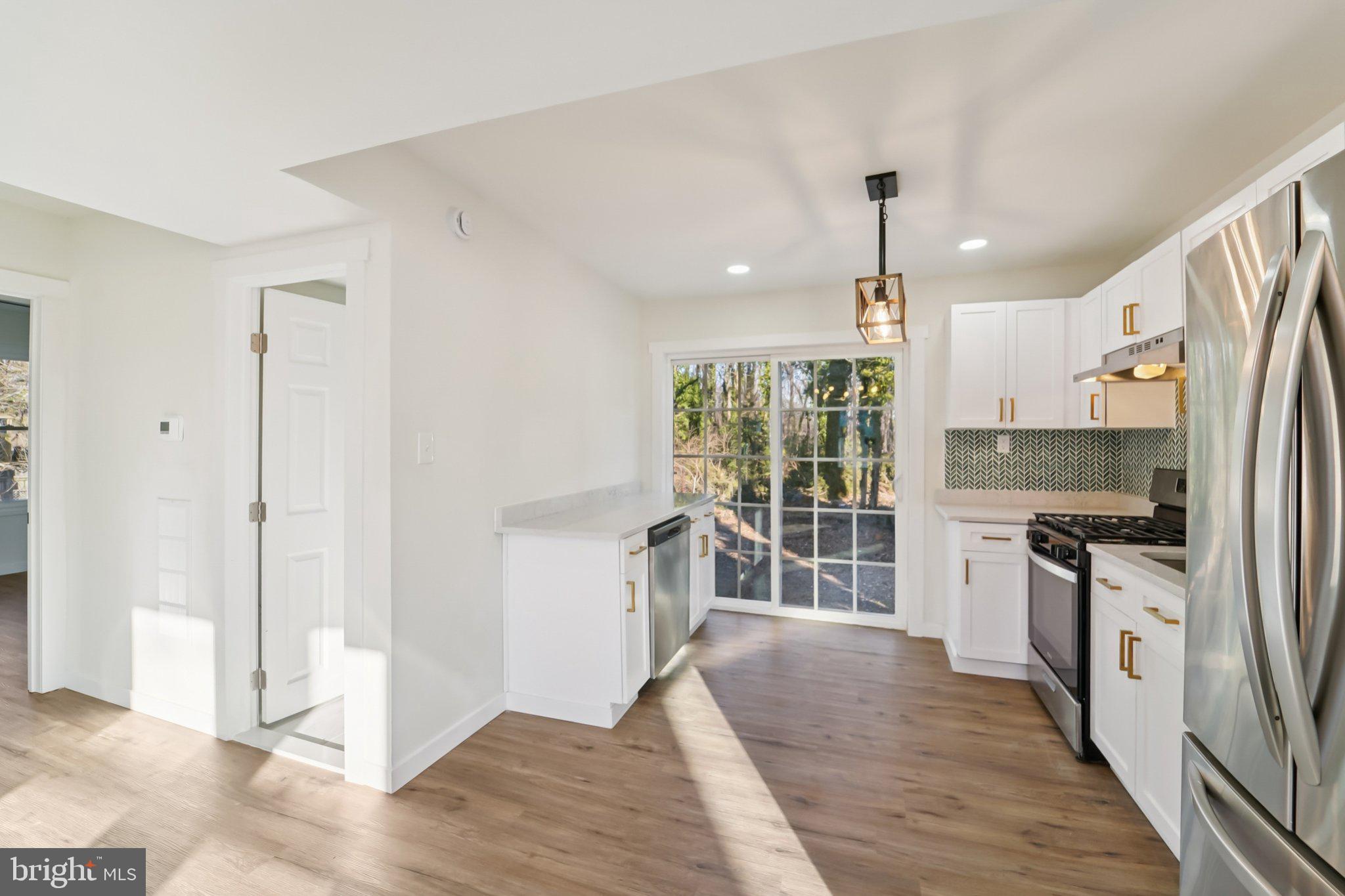 27 Pelczar Avenue Baltimore, MD 21221 - Photo 11 of 40 a open kitchen with stainless steel appliances granite countertop a stove a refrigerator a sink and a oven with wooden floor