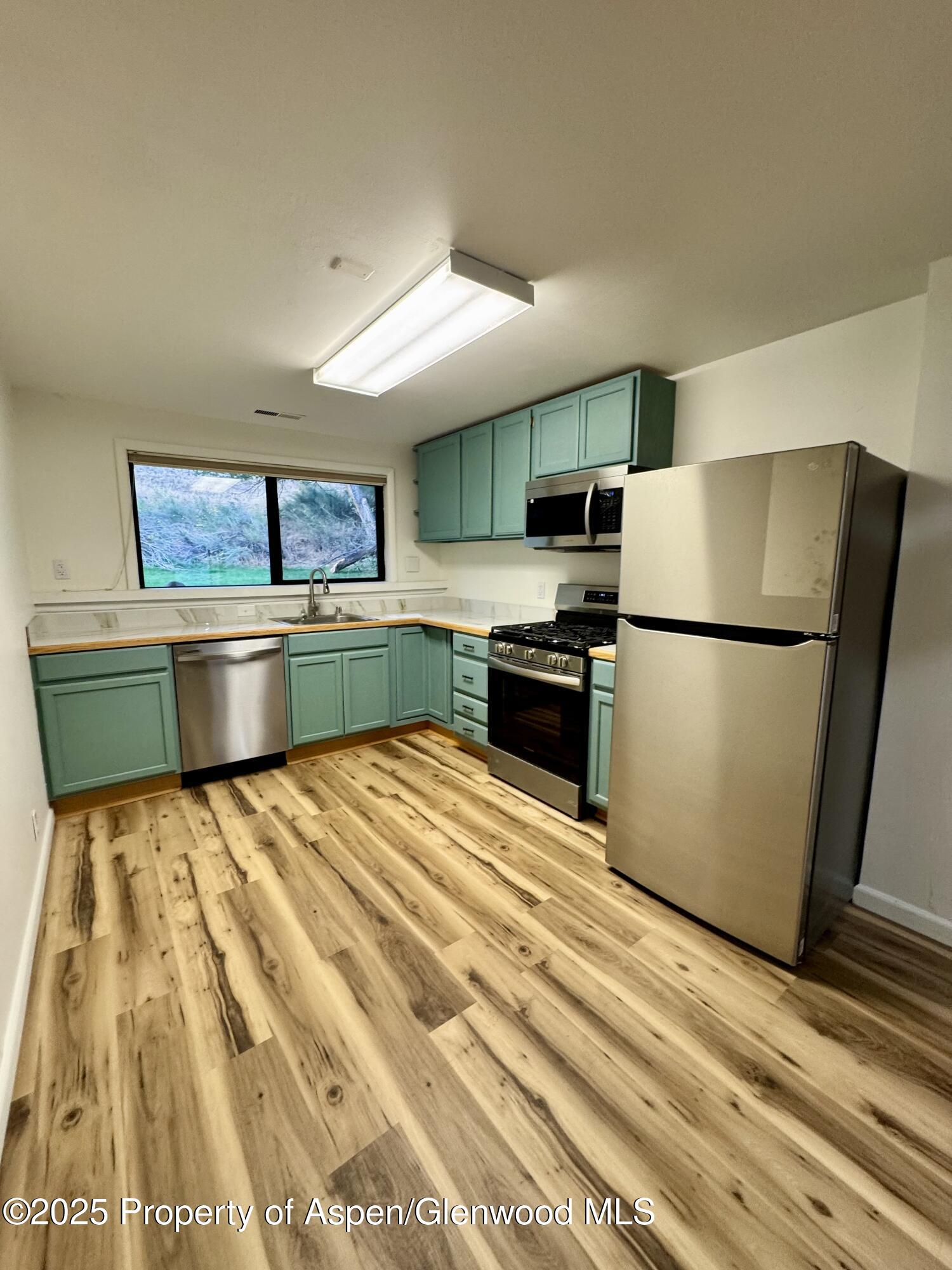 228 North 7th Street New Castle, CO 81647 - Photo 8 of 24 a kitchen with granite countertop a refrigerator and a stove top oven