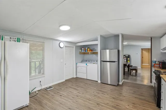a kitchen with a refrigerator and a wooden floor