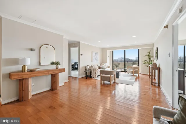 a living room with couches and kitchen view with wooden floor
