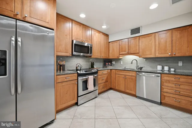 a kitchen with stainless steel appliances granite countertop a stove a sink and a refrigerator