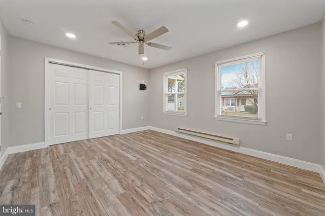 a view of empty room with wooden floor and fan