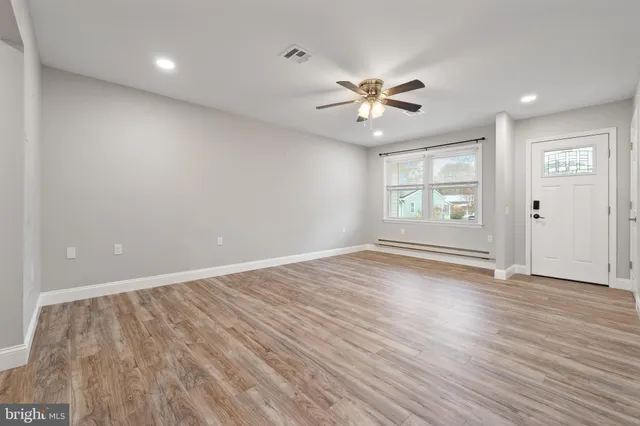 an empty room with wooden floor fan and windows